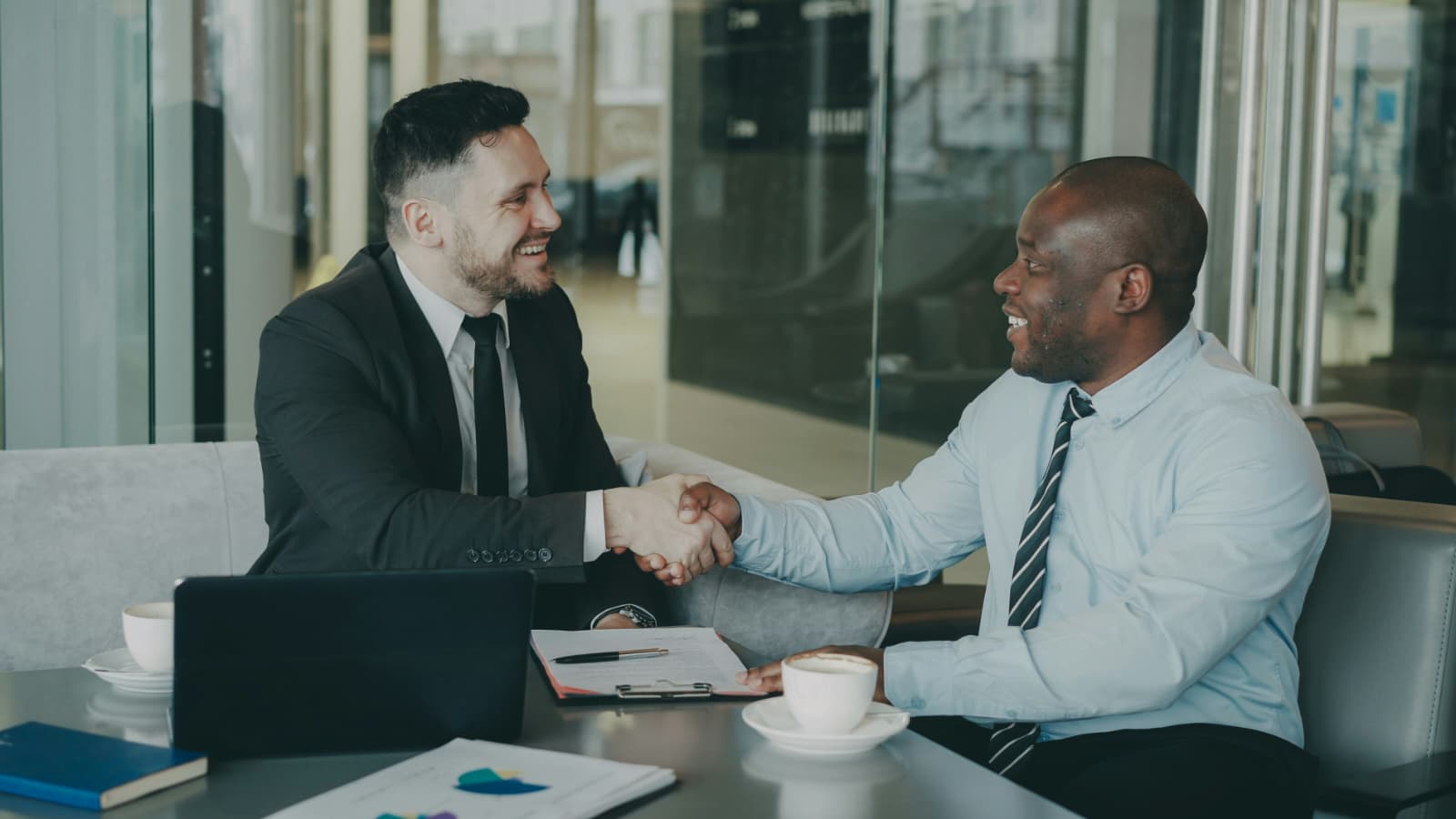 Two business professionals shaking hands across a meeting table