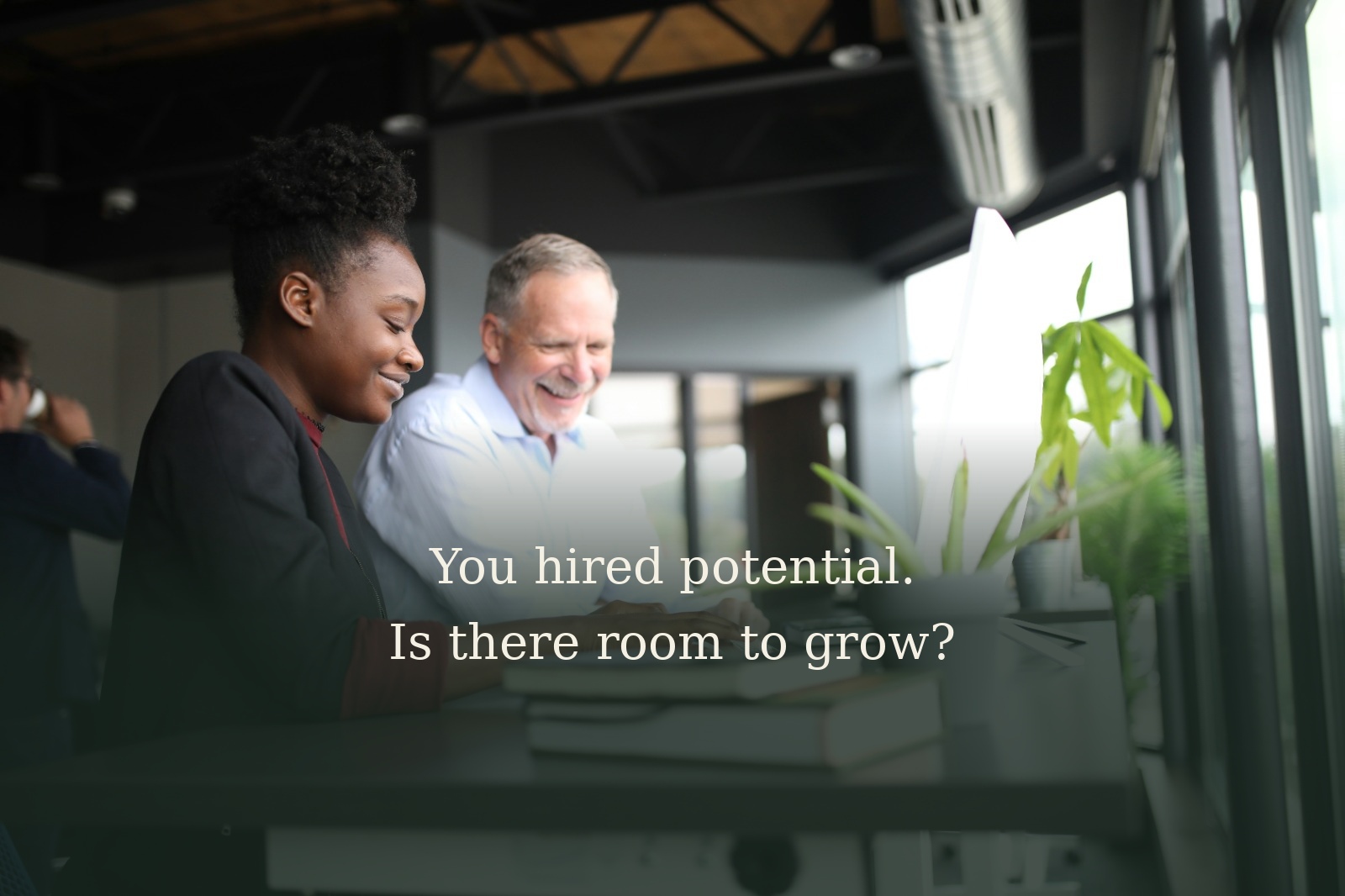 Two colleagues working together at a computer, with the text "You hired potential. Is there room to grow?"
