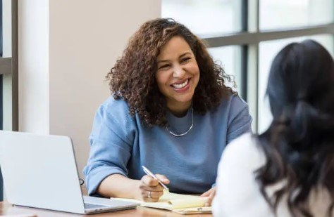 Smiling leadership coach taking notes during a one-on-one coaching session