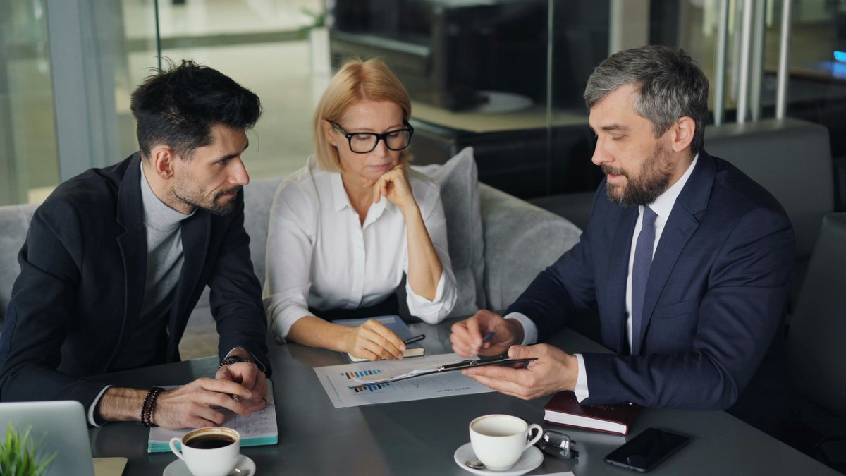 Three business colleagues reviewing a chart together at a table in a café
